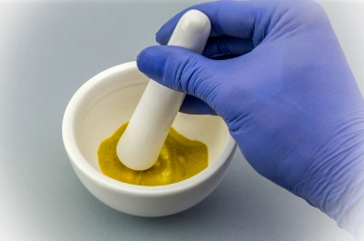 White bowl with ingredients being mixed for a cosmetic product in a lab.